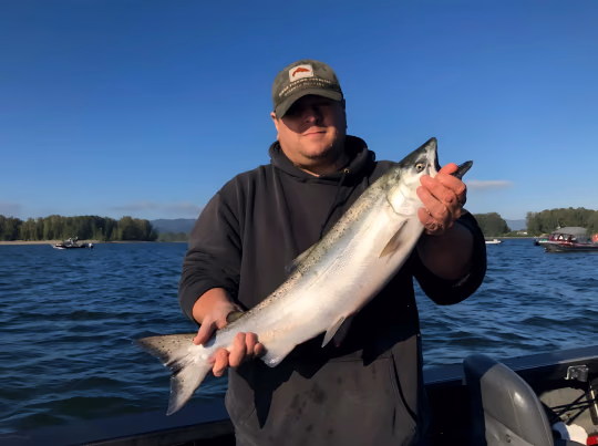 Angler in a cap holding a large silver fish on the water