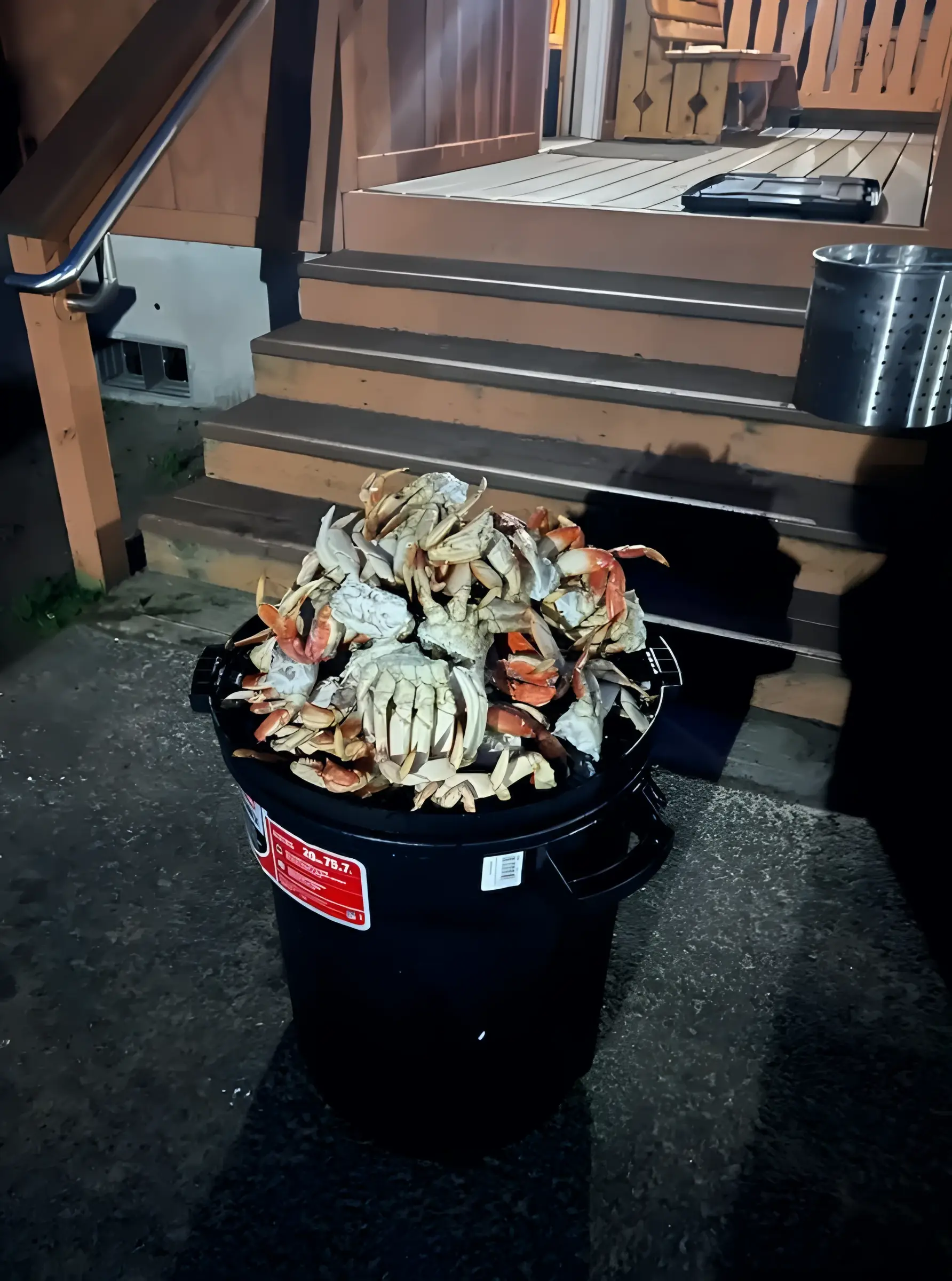 Black bin heaped with Dungeness crab in front of wooden steps