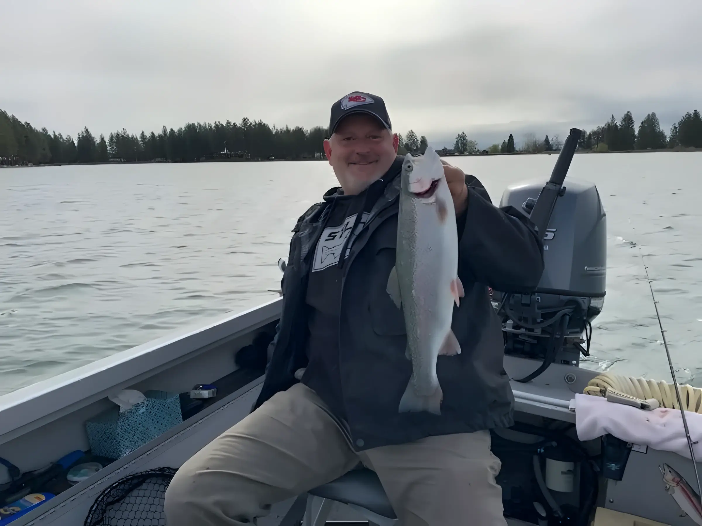 Angler seated on a boat holding a silver fish