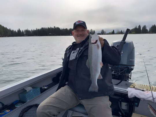Angler seated on a boat holding a silver fish