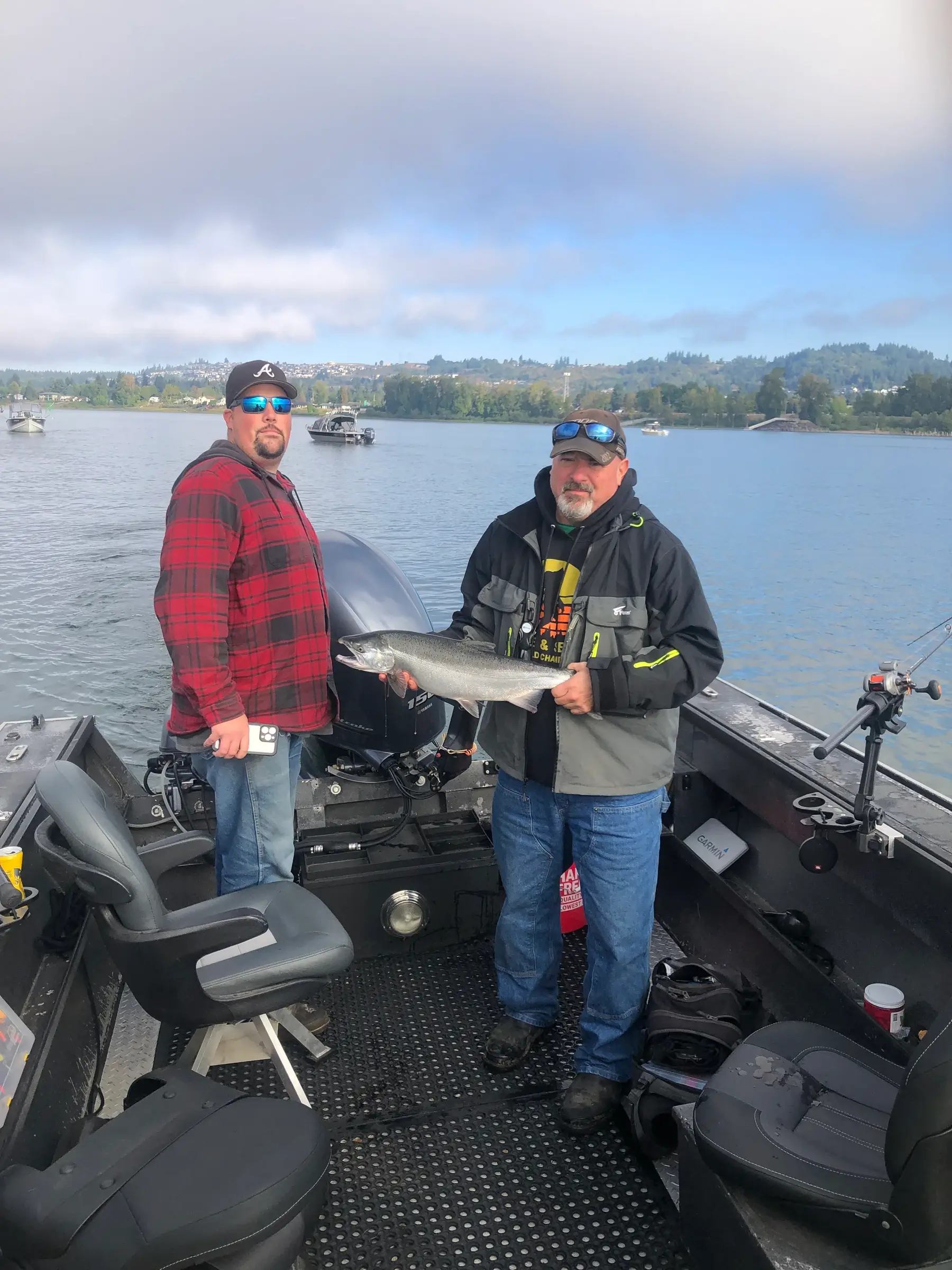 Two anglers on the deck of a sled boat holding a fish between them